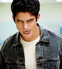 a young man wearing a denim jacket and a white shirt is looking at the camera .