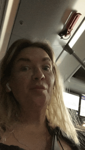 a woman wearing ear buds is looking at the camera