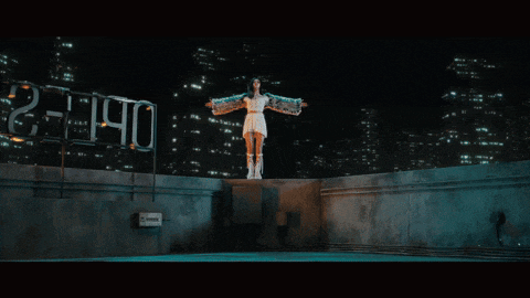 a woman in a white dress is standing on top of a building with a sign that says 21:10