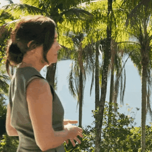 a woman in a green dress is standing in front of palm trees .