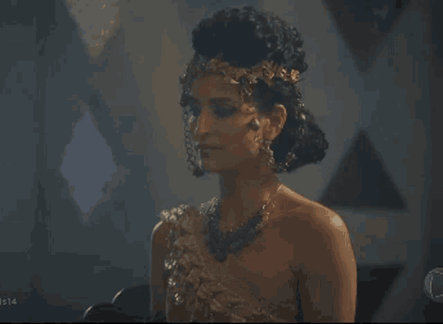 a woman with a crown on her head and a necklace with the number 14 on the bottom right