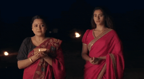 two women in red saris are standing next to each other