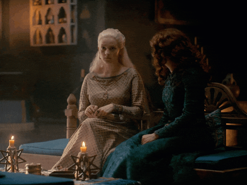 a woman in a green dress sits next to a woman in a white dress