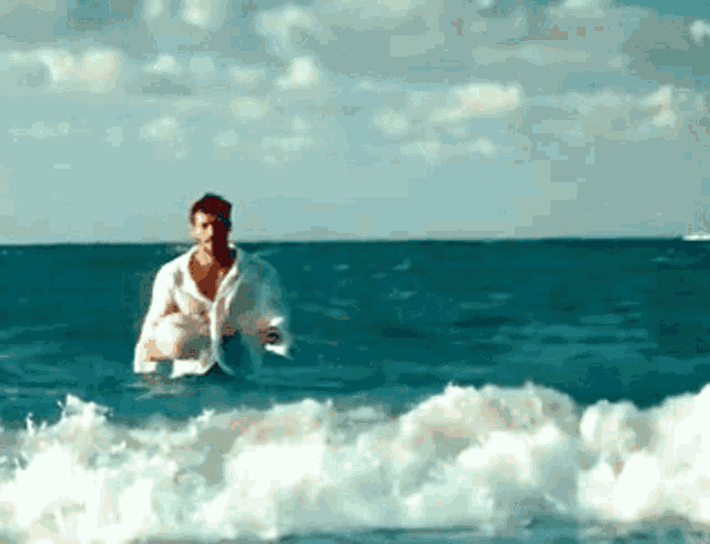 a man in a white shirt is in the ocean