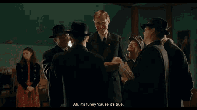 a group of men are standing in a room and one of them says " ah it 's funny cause it 's true "