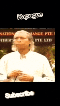 a man in a white shirt is standing in front of a sign that says kapugee