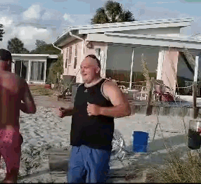 a man in a black tank top stands on a beach