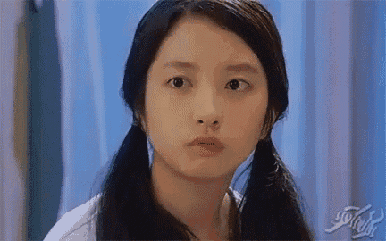 a young girl with pigtails is looking at the camera .