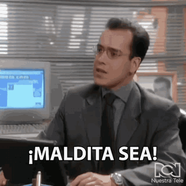 a man in a suit and tie is sitting in front of a computer with the words maldita sea above him