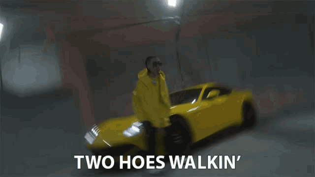 a man standing next to a yellow car with the words two hoes walkin ' on the bottom