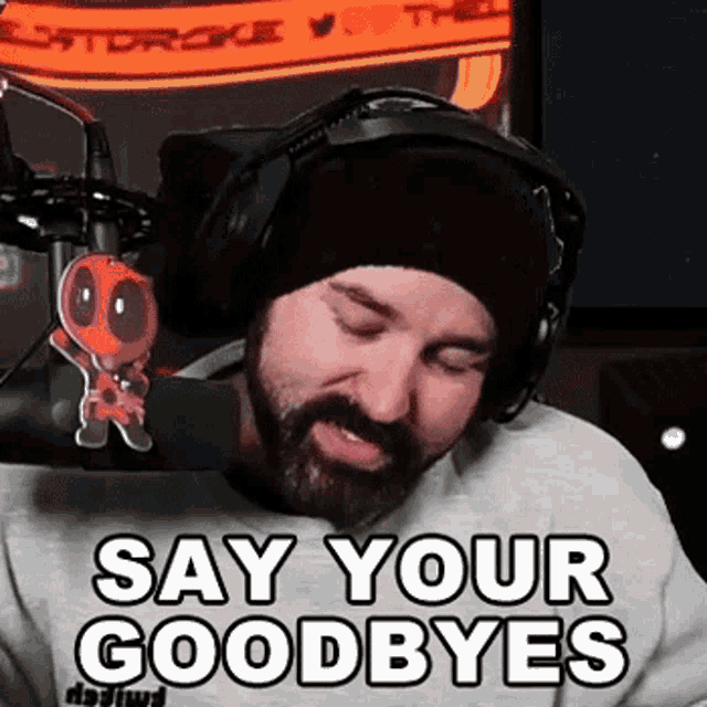 a man with a beard and headphones is standing in front of a microphone .