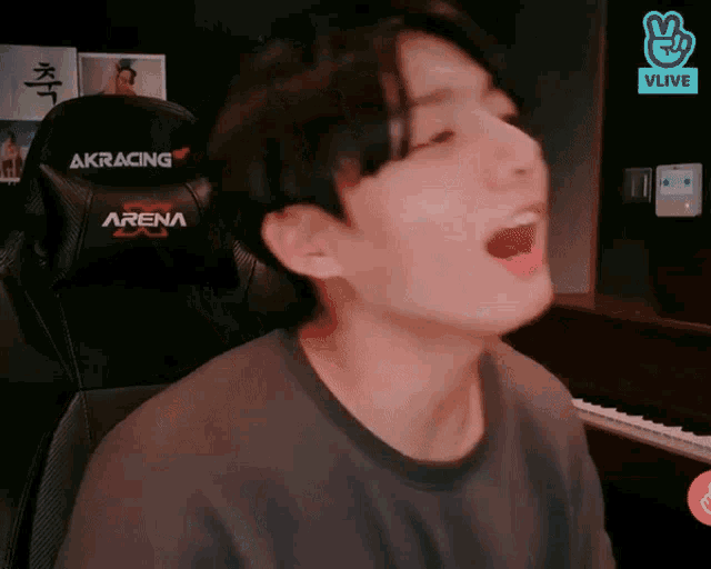 a man is singing in front of a keyboard and a chair that says arena