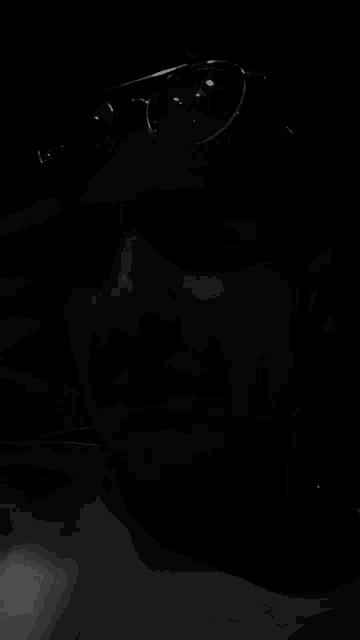 a close up of a person 's face in the dark wearing sunglasses .