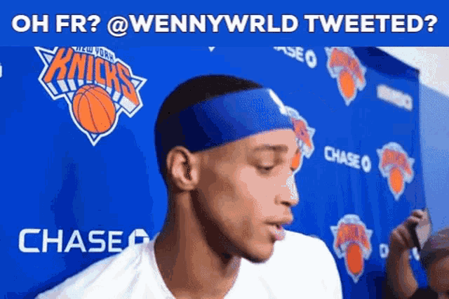 a man wearing a headband stands in front of a new york knicks banner