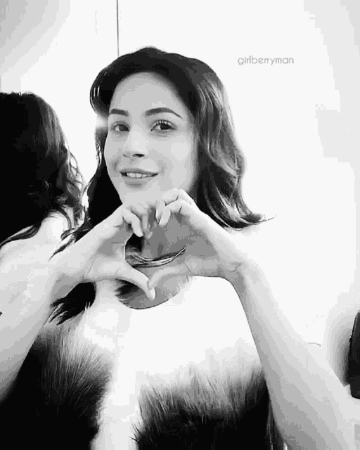 a woman making a heart shape with her hands in front of a mirror
