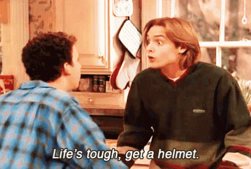 two men are talking in a kitchen with one saying life 's tough get a helmet