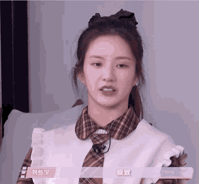 a woman wearing a plaid shirt and a sweater with chinese writing