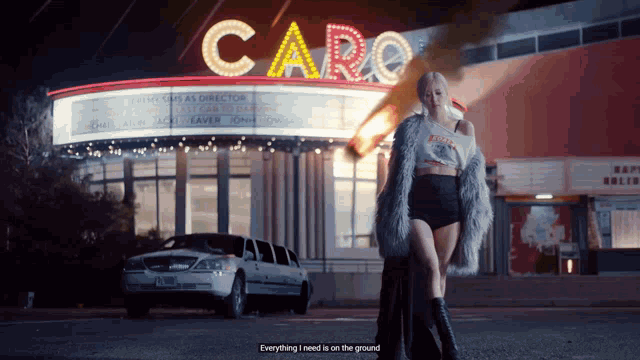 a woman in a fur coat stands in front of a building that says care