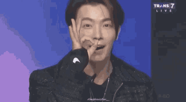 a close up of a person making a heart shape with their hands on their face .