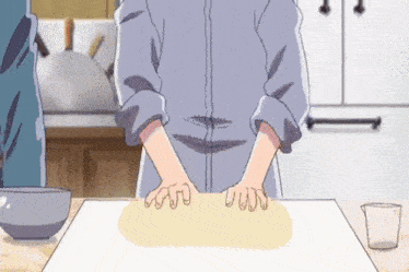 a person is kneading dough on a table with their hands