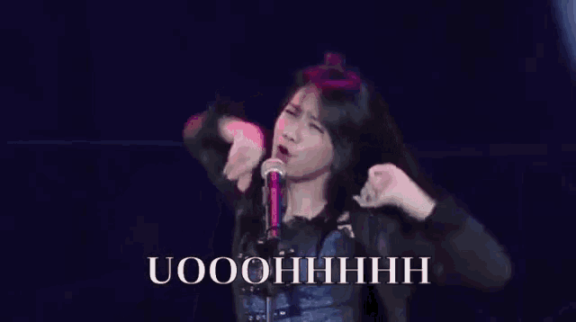 a woman is singing into a microphone with the words uooohhhhh written on the bottom of the image .