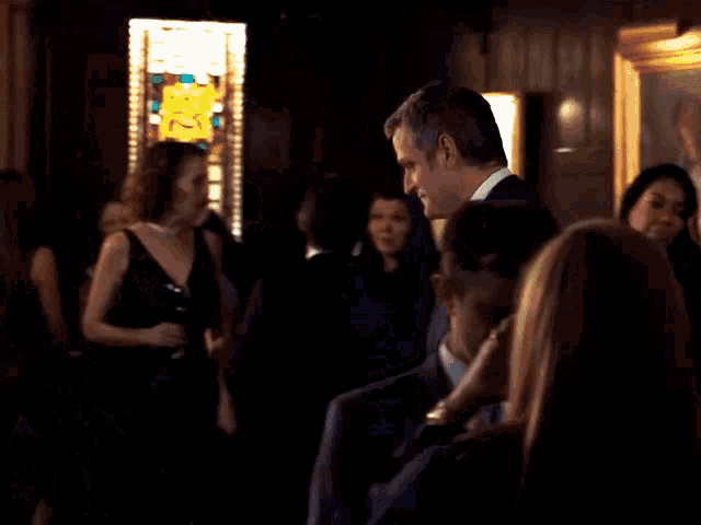 a man in a suit stands in a crowded room