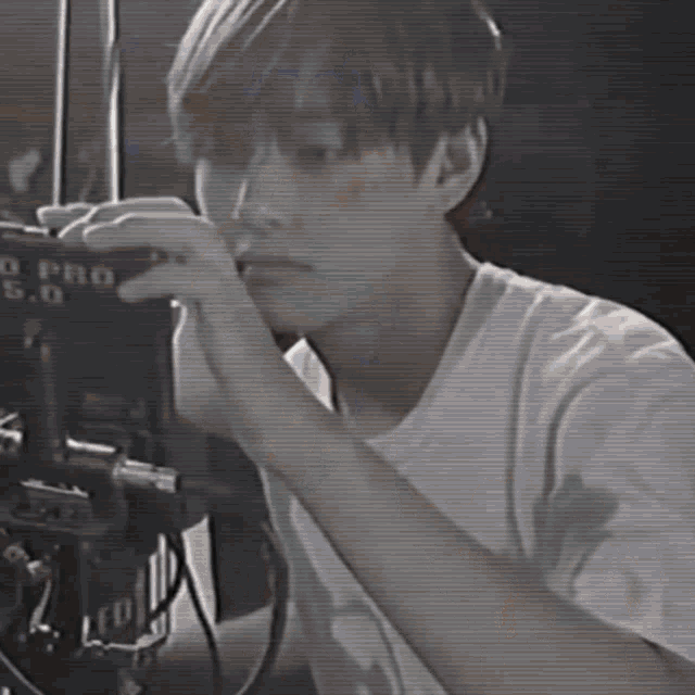 a man in a white t-shirt is looking at a camera that says o pro 5.0