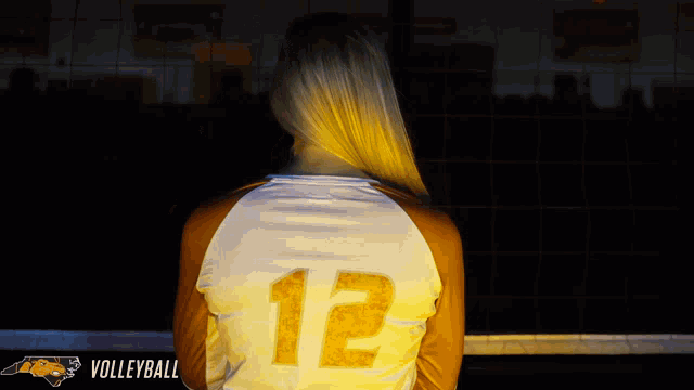 a woman wearing a volleyball jersey with the number 12 on the back