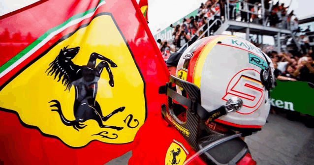 a man in a ferrari helmet is standing next to a flag .