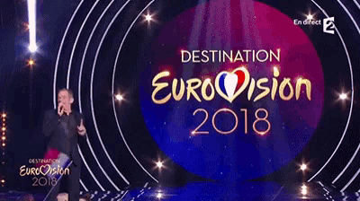 a man is standing in front of a stage that says destination eurovision 2018 on it