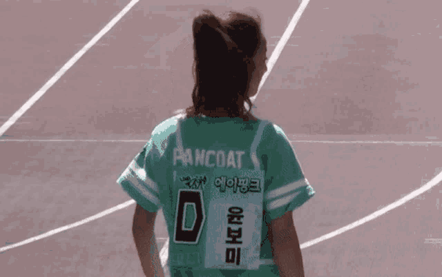 a girl wearing a green shirt with the number d on it