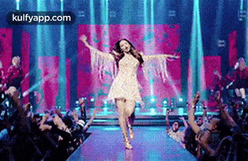 a woman in a white dress is walking down a runway in front of a crowd .
