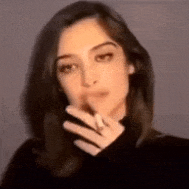 a close up of a woman smoking a cigarette in a blurry photo .
