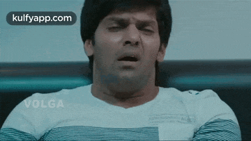 a man is making a funny face while sitting on a bed .