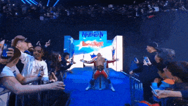 a man in a red white and blue outfit stands in front of a sign that says american wrestler