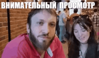 a man with a beard and a woman with long hair are sitting next to each other .