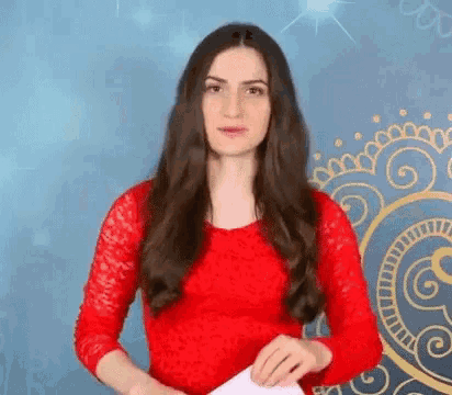 a woman in a red dress is holding a piece of paper in her hands .