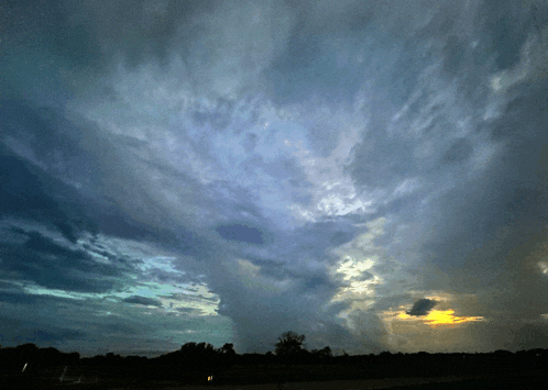 a dark cloudy sky with a sunset in the distance