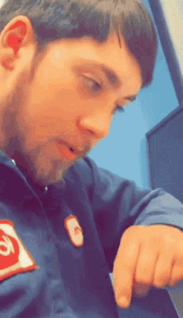 a man wearing a blue jacket with a red patch that says g on it