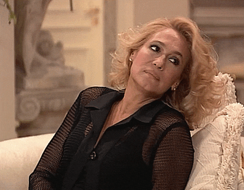 a woman in a black shirt is sitting on a couch looking up