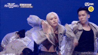 a group of people are dancing in front of a mnet sign