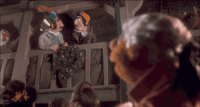 a group of cartoon characters are standing on a balcony with a wreath on it