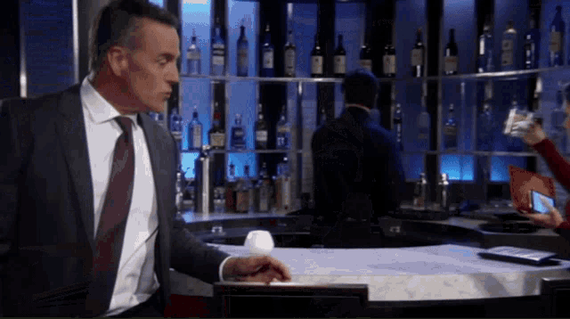 a man in a suit stands in front of a bar