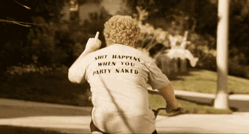 a man riding a bike with a shirt that says shit happens when you party naked
