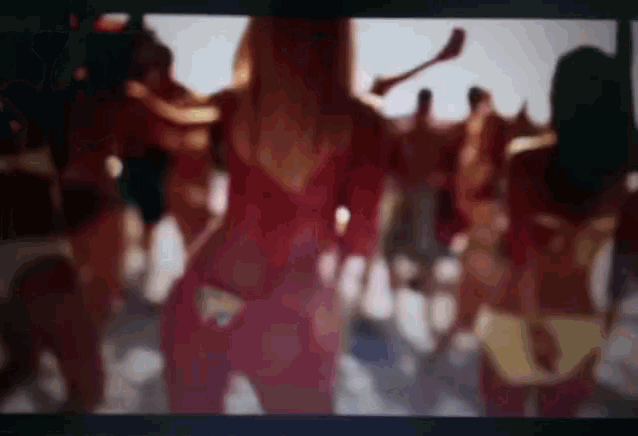 a blurry picture of a woman in a red dress dancing in a crowd