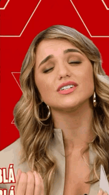 a woman is making a funny face in front of a red background that says bla