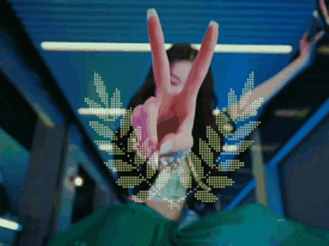a woman in a green dress making a peace sign with her hands