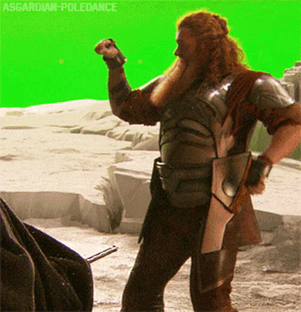 a man in armor stands in front of a green screen that says asgardian-poledance on it