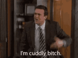 a man in a suit and tie is standing in a room and says i 'm cuddly bitch .