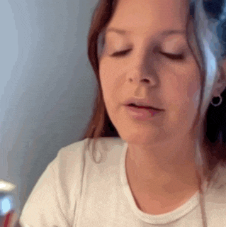 a woman in a white shirt is sitting at a table with her eyes closed .